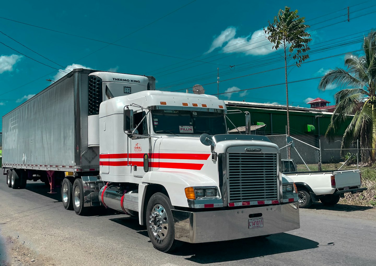 White semi-trailer truck with red stripes parked on a road.