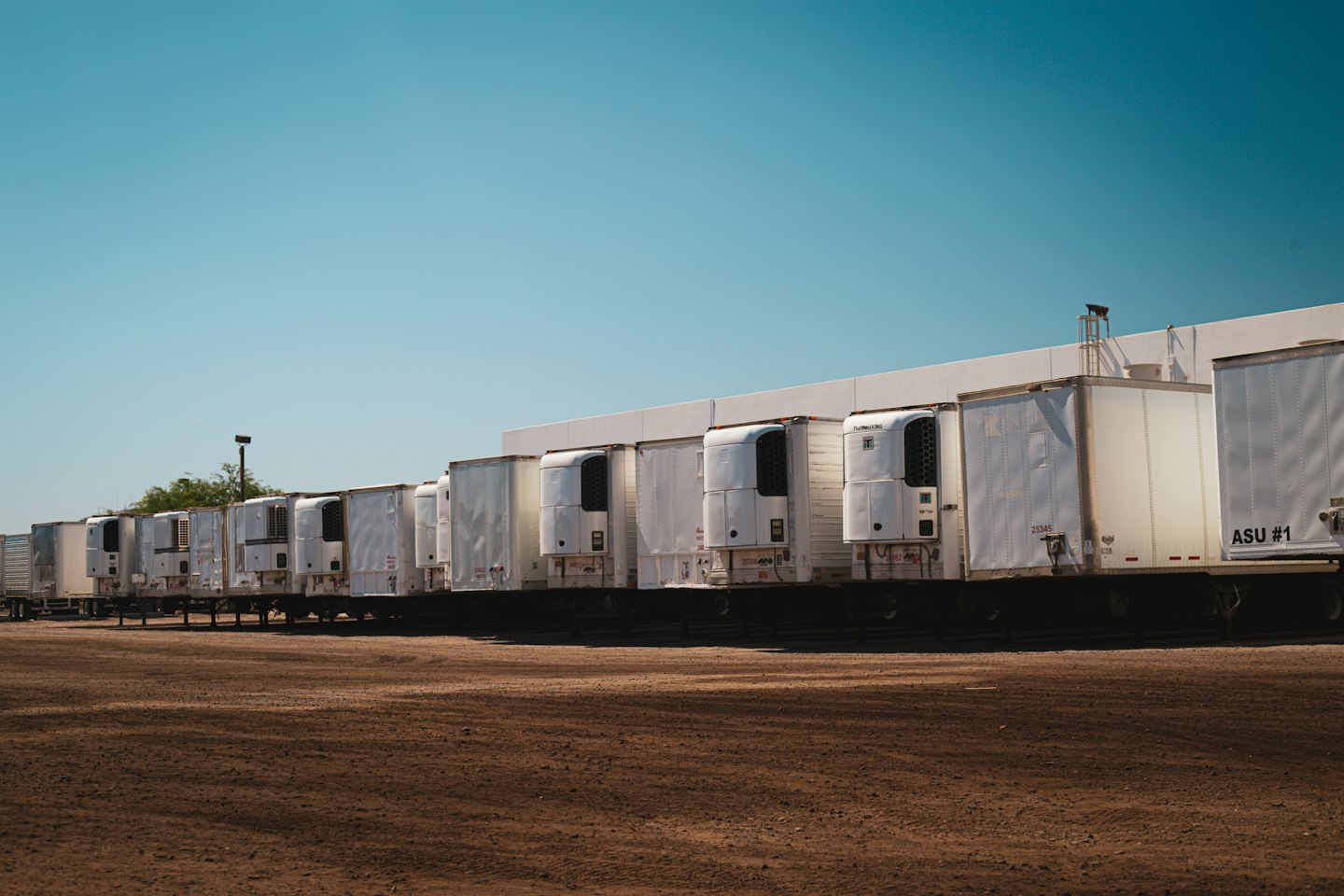White refrigerated semi-trailers parked at a loading dock.